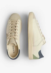 Baskets en cuir beige avec un bout en suede texturé, design minimaliste, accents de talon contrastants en bleu marine et vert, et lacets plats.