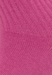 Różowa dzianina o gładkiej teksturze z pionowym wzorem ściągacza, tworząca elastyczny i komfortowy design.