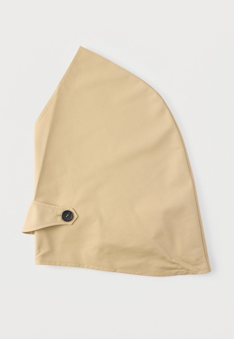 Beige Baumwollkapuze mit spitz zulaufender Form und Knopfverschluss an der Seite; glatte Textur und schlichtes Design.