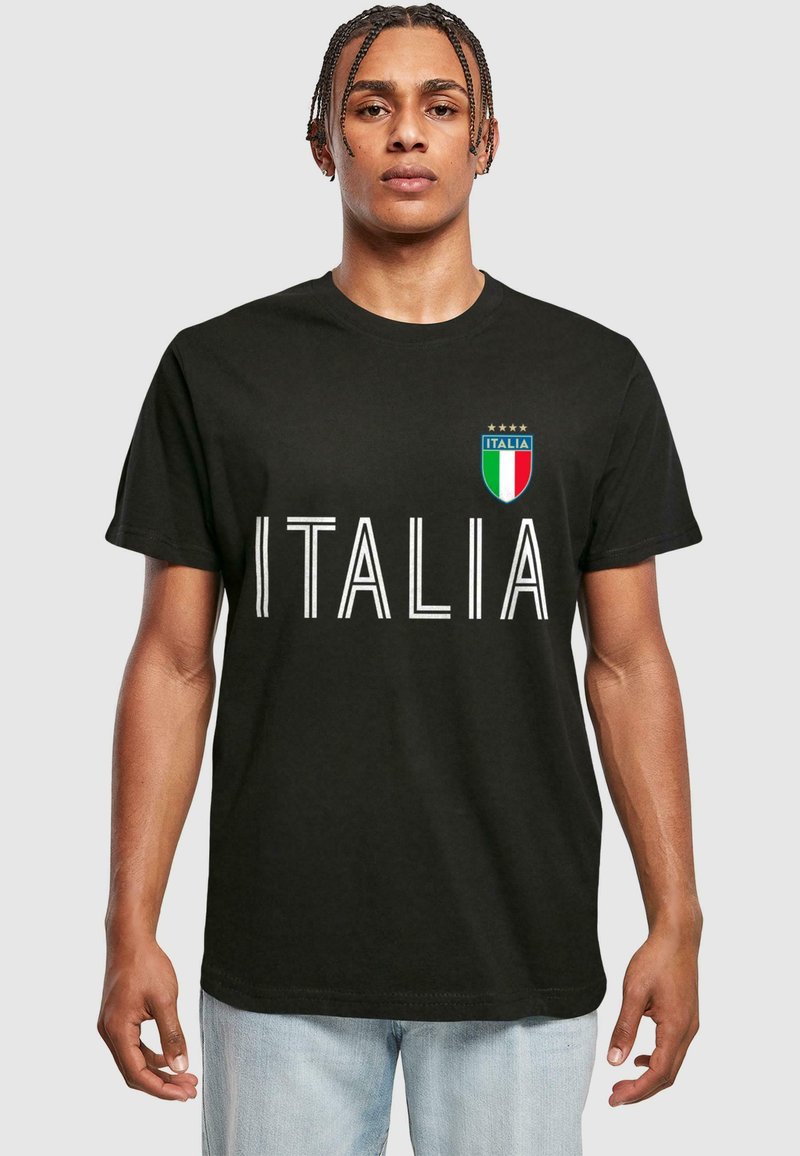 Juodas medvilnės marškinėliai su užrašu "ITALIA" ryškiu baltu šriftu ir mažyte Italijos vėliavos emblema su trimis auksinėmis žvaigždėmis kairėje krūtinės pusėje.