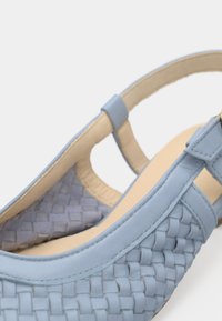 Γαλάζιο πλεκτό δερμάτινο σανδάλι με λουράκι γύρω από τη φτέρνα, μπεζ εσωτερική σόλα και ρυθμιζόμενο λουράκι.