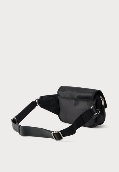 Μαύρο ρυθμιζόμενο νάιλον τσαντάκι μέσης με κεντρικό διαμέρισμα με φερμουάρ και μπροστινή τσέπη με καπάκι σε λευκό φόντο.