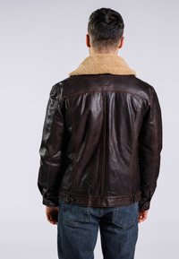 Braune Lederjacke mit einem hellbraunen Schaffellkragen, Knopfverschlüssen und einer glatten Textur. Die Ansicht von hinten zeigt die Nähdetails.