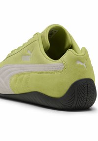 Zapatillas de ante verde lima con acentos en blanco y suela de goma texturizada. Presentan la marca Puma y un diseño elegante y curvado.