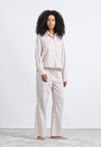 Lichtbeige linnen loungewear set met een gekort ma blouse met lange mouwen en een brede broek, met een gestructureerde afwerking.