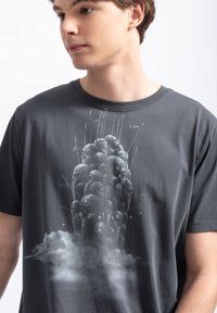 Grijze katoenen t-shirt met een grafisch ontwerp van gestileerde hoofden en wolkmotieven in monochrome tinten. Ronde hals en korte mouwen.
