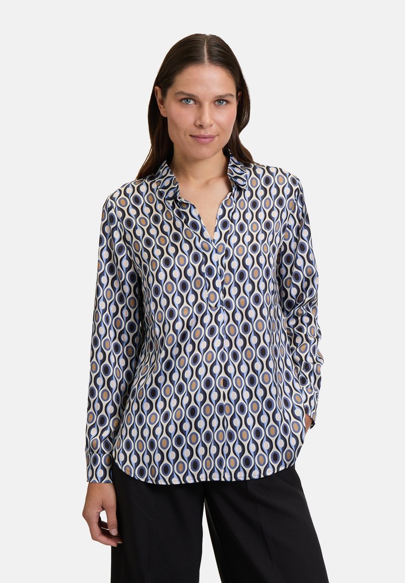 Maglietta a maniche lunghe in un tessuto setoso con un motivo geometrico di cerchi interconnessi nei colori blu navy, crema e oro, con colletto.