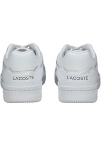 Weiße Lacoste-Sneaker mit einem glatten Lederoberteil, runder Zehenpartie und dezentem Branding an der Ferse. Strukturierte Gummisohle für besseren Halt.