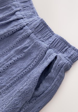 Tessuto azzurro chiaro con trama e design decorativo, elastico in vita, caratterizzato da forme a diamante e piccoli ritagli.