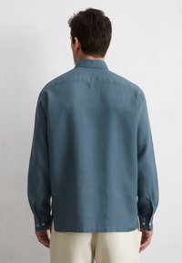 Long-sleeve shirt in muted blue fabric, featuring a button-down collar, buttoned cuffs, and a straight hem with a relaxed fit.