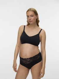 Grūtniece, kas valkā melnu barošanas krūšturi un melnus māmiņu apakšveļas biksītes ar mežģīņu apmalēm uz vienkārša baltā fona.