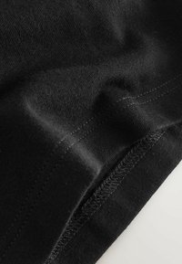 Fekete pamutvászon sima textúrával, finom nyúlással és kontrasztos varrási varrattal. Puha, rugalmas és gyűrődésálló.