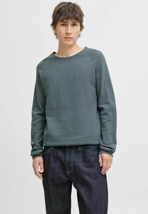 Groene textured sweatshirt met een brede halslijn en lange mouwen, gecombineerd met donkere spijkerbroek. Eenvoudig ontwerp zonder zichtbare patronen of accenten.