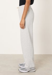 Svetlošedé tepláky z mäkkej látky s elastickým pásom a šnúrkou. Majú rovné nohavice a voľný strih.