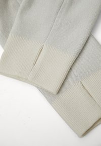 Ανοιχτό γκρι μανίκια πουλόβερ με υφασμάτινη υφή και κρεμ ριμπ μανσέτες. Διαθέτει πλευρικές σχισμές, προσφέροντας έναν αντίθετο συνδυασμό χρωμάτων.