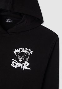 Felpa nera con cappuccio caratterizzata da una grafica bianca con un orso e il testo "SONO SOLO UN ORSO." Realizzata in tessuto morbido con una vestibilità comoda.