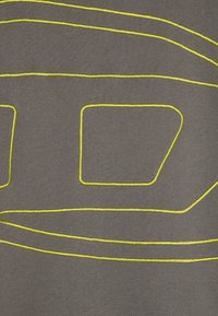 Tessuto grigio decorato con audaci ricami gialli, con forme angolari e curve che creano un design geometrico. La trama appare liscia e morbida.