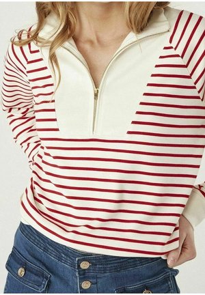 Pull à rayures rouges et blanches avec col zippé, présentant un panneau avant entièrement blanc et des manches longues. Tissu doux, coupe décontractée.