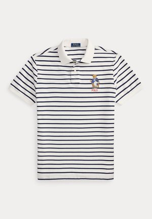 Biała koszulka polo z granatowymi poziomymi paskami, wyszywany niedźwiedź w marynarce na lewej piersi oraz napis „POLO” pod niedźwiedziem.