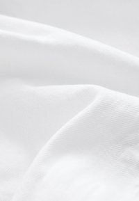 Biela bavlnená látka s hladkou textúrou, so mäkkými záhybmi a jemným leskom, predstavujúca jednoduchý, jednotný vzor.