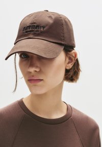 Căciulă de baseball maro cu text brodat "DETROIT", având o margine curbată și un design cu șase panouri. Purtați cu o cămașă maro asortată.