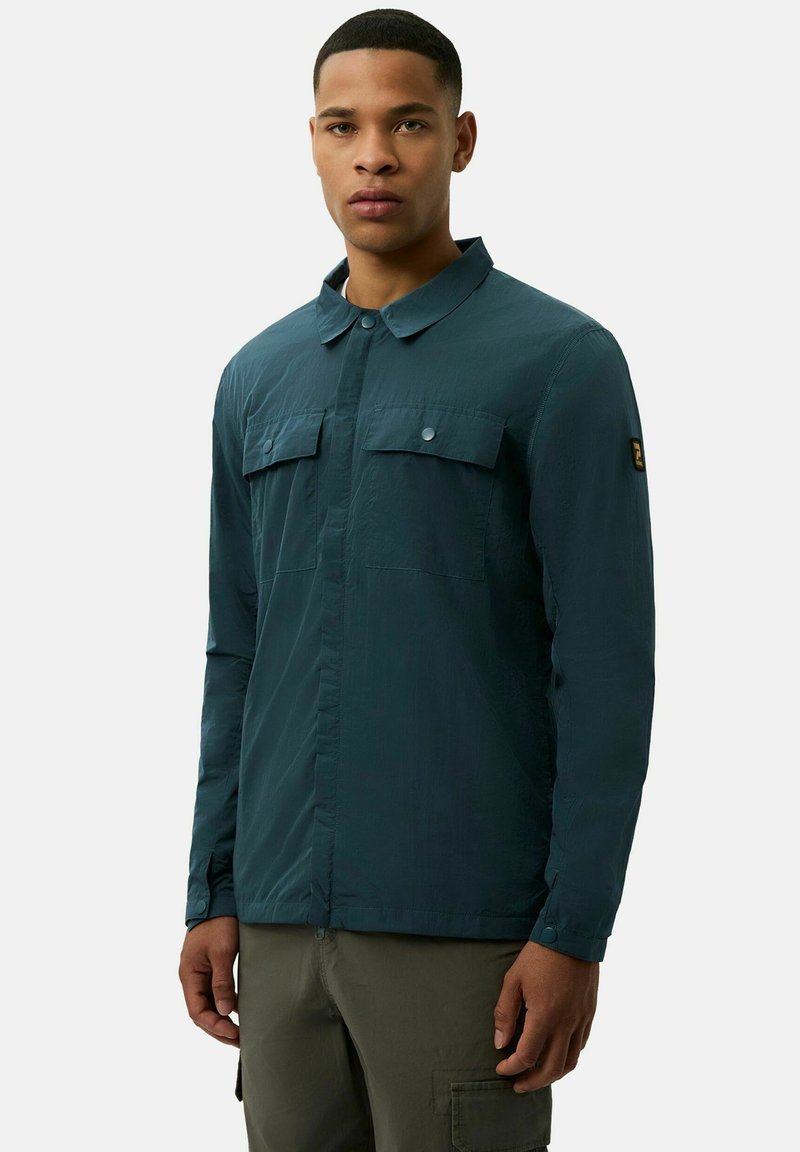 Miętowa, lekką koszula z zapięciem na guziki z przodu, dwiema kieszeniami na piersi i długimi rękawami z guzikami przy mankietach. Gładki, teksturowany materiał.