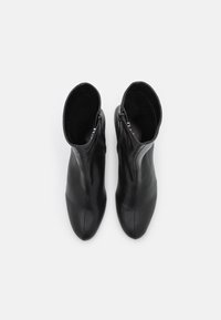 Une paire de bottines en cuir noires avec des zips latéraux, vue de dessus sur un fond blanc.