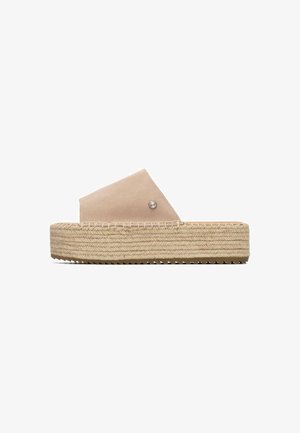 Beige suede espadrille slide sandal with a wide upper strap and a braided jute platform sole, featuring a decorative silver accent.