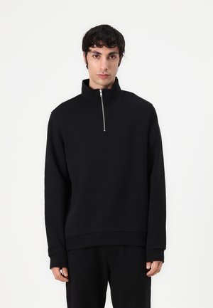 Felpa nera con collo alto e chiusura a mezza zip. Presenta maniche lunghe e una vestibilità comoda. Realizzata in un tessuto morbido e strutturato.