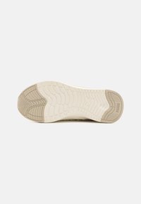 Sole of a sneaker in beige and light cream, featuring textured patterns for grip and reinforcement. Brand logo present.