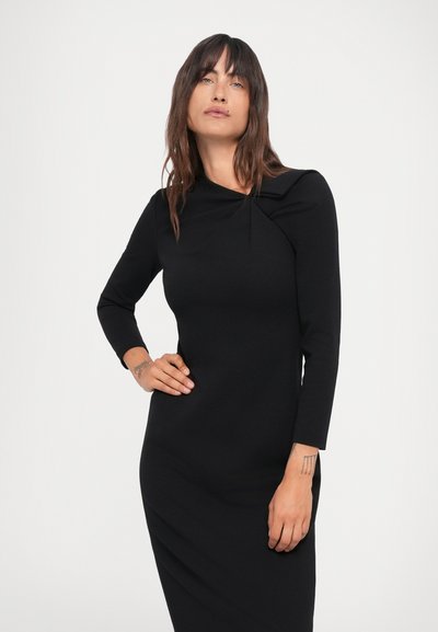 Melnas pieguļošas kleitas ar garām piedurknēm, ar drapētu dekoltē un nelielām šuvēm. Gluda, elastīga auduma ar elegantu siluetu.