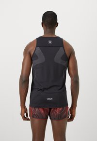 Sort atletisk tanktop med et geometrisk mesh-mønster på siderne, med kontrastfarvet hvid syning og et logo ved nakken.