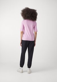 Ljusrosa t-shirt med kort ärm som matchas med svarta tapered joggers och vita sneakers. Slät tygkvalitet med elastiska ärmslut och midjeband.