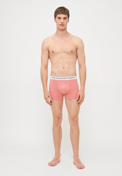 Roze bokserice sa uskim krojem, s bijelim elastičnim pojasom označenim "POLO RALPH LAUREN." Glatka tekstura tkanine, minimalistički dizajn.
