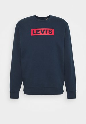 Sweat-shirt bleu marine à col rond et manches longues, avec un rectangle rouge portant l'inscription "LEVI'S" en lettres noires audacieuses, centrée sur la poitrine.