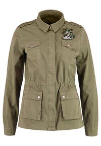 Oliivinvihreä puuvillatakki, jossa kapea vyötärö, kaksi etutaskua läpällä ja vasemmassa olkapäässä kukkakirjailu. Takissa on napsautettavat napit.