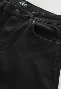 Mustad denim teksad mustas värviga ja lõdva lõikega, millel on nupuga sulgemine, küljetaskud ja õmbluste juures peened õmblused.