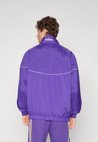Lila szélálló kabát, rugalmas mandzsettákkal és aljjal, a gallérján "Lakers" hímezve. Simogató, könnyű anyag.