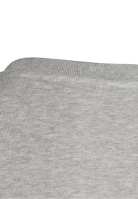 Nahaufnahme eines grauen Strickstoffs, die Textur und die Naht eines gefalteten Kleidungsstücksaums zeigend.