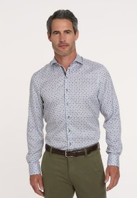Lange mouwen knoophemd van lichtblauwe stof, met een geometrisch patroon in donkerblauw, bruin en wit. Brown knopen en kraag.