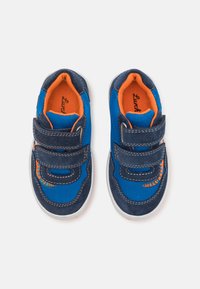 Μπλε παιδικά παπούτσια φτιαγμένα από πλέγμα με σουέτ λεπτομέρειες. Διαθέτουν δύο ρυθμιζόμενες στενές ταινίες από Βέλκρο και πορτοκαλί εσωτερική επένδυση.
