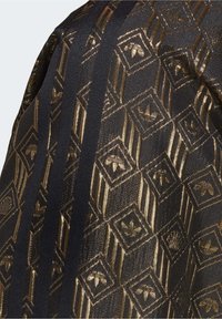 Černá tkanina se zlatým geometrickým vzorem, který zahrnuje čtverce a květinové motivy; doplněná černými pruhy podél jedné strany. Texturovaný, metalický lesk.