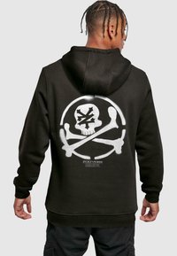 Felpa nera con cappuccio caratterizzata da una grande grafica di un teschio e due ossa incrociate bianche sul retro, con la scritta "ZOO YORK" sotto. Tessuto morbido.