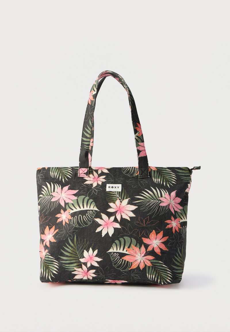 Sac cabas noir avec motif floral tropical rose et vert, deux poignées, et une petite étiquette "Roxy" à l'avant.