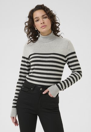 Pull à col roulé rayé gris et noir avec manches longues, présentant un col côtelé et des poignets repliés, associé à un jean noir taille haute.