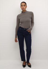 Sivkasti rebrasti dolg rokav top v kombinaciji z temno modrimi ravnimi jeans hlačami. Črne balerinke z ostrim nosom dopolnjujejo outfita. Enostaven dizajn, prilegajoča silhueta.