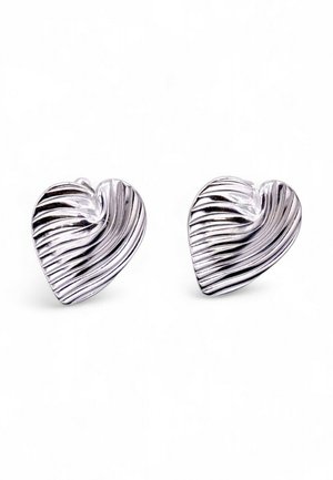Orecchini a forma di cuore in argento con un design ondulato e testurizzato. Ogni orecchino presenta sottili scanalature e una finitura lucida.