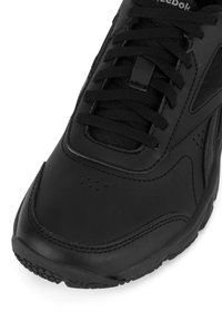 Musta spordi jalanõud tekstuuriga nahkdetailidega pealses, ümmargune toe, pehmendusega keel ja detailne nööride sulgemine. Omab sälgukeid, et tagada õhupääs.