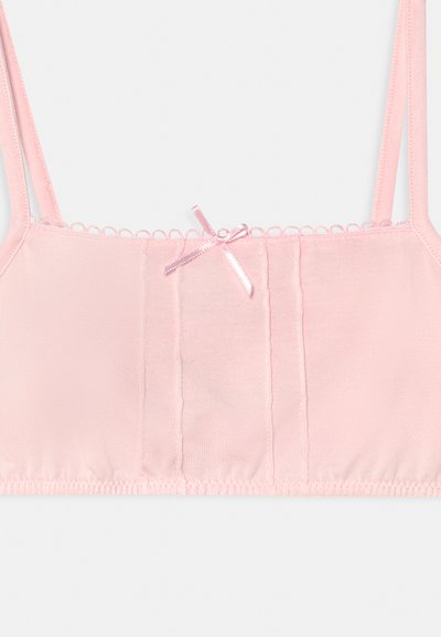 Bralette rosa claro com alças ajustáveis, um laço central decorativo, bordas onduladas e um acabamento suave. Apresenta seções para um design adicional.