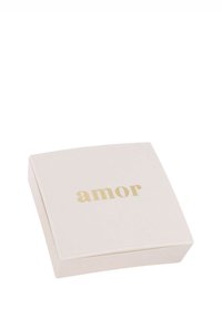 Stängd ljusrosa fyrkantig smyckeslåda med guldskrift "amor" centrerad på locket mot en vit bakgrund.